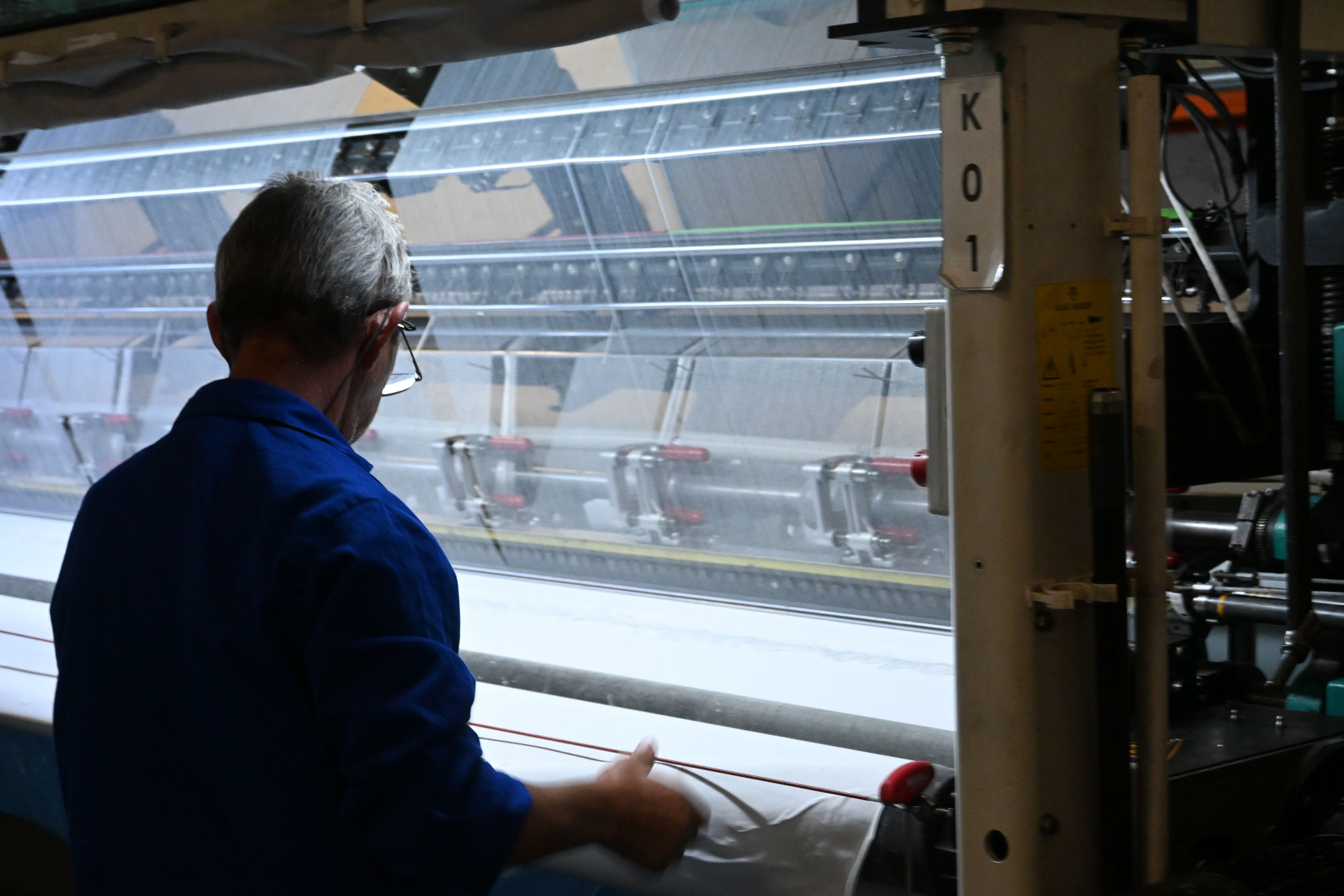 Technician monitoring fabric on warp-knit machine K01