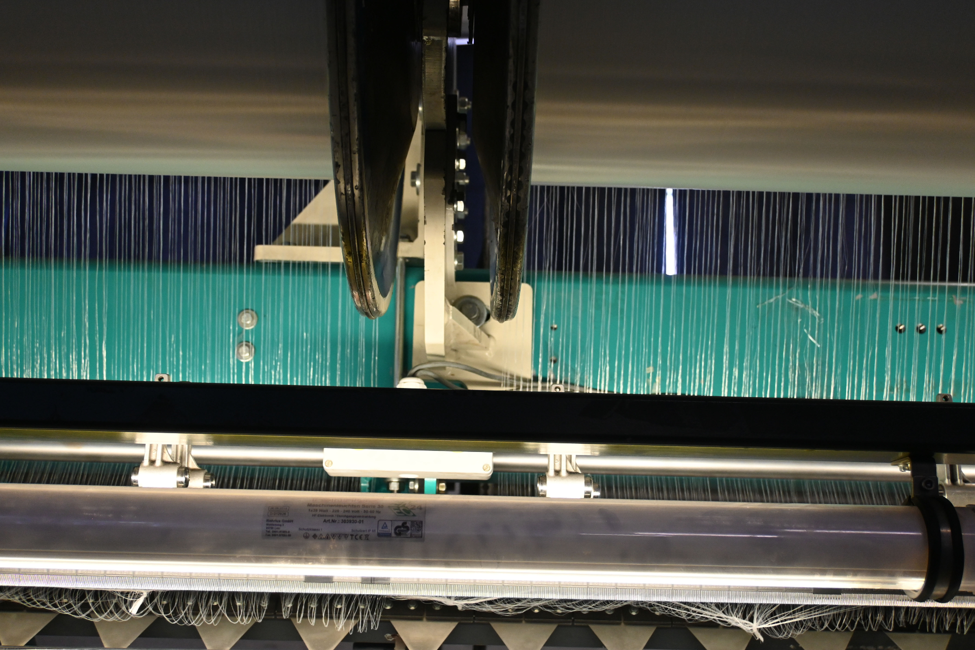 Close-up of warp-knit machine guide bar and needle action