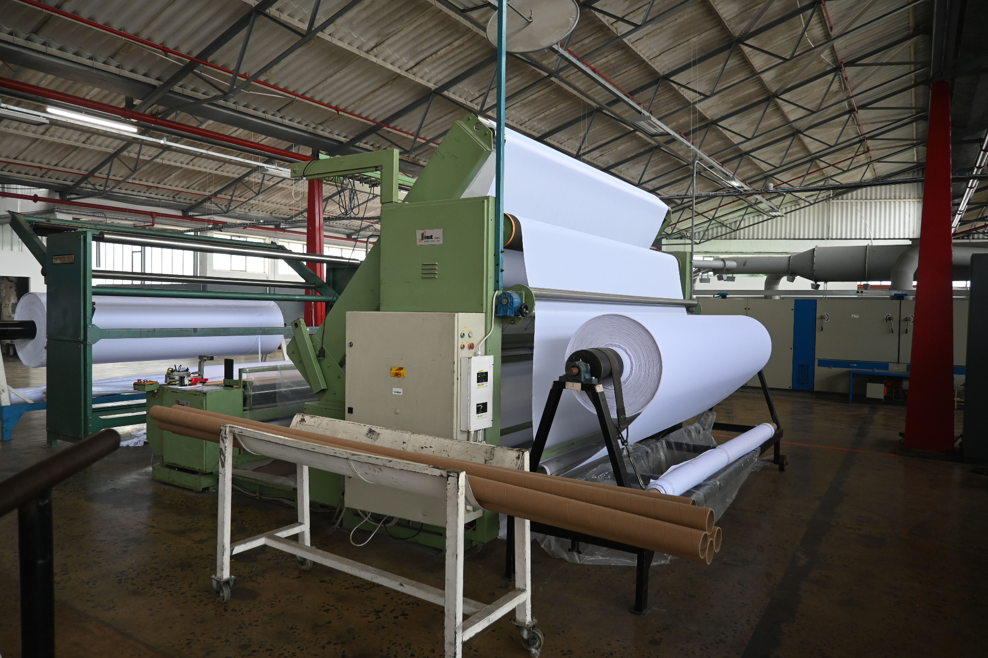Wide-format finishing machine winding a large roll of white printable fabric